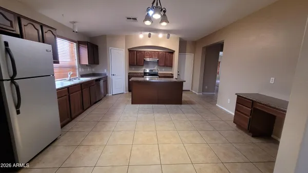 a large kitchen with granite countertop a refrigerator a stove top oven and a sink