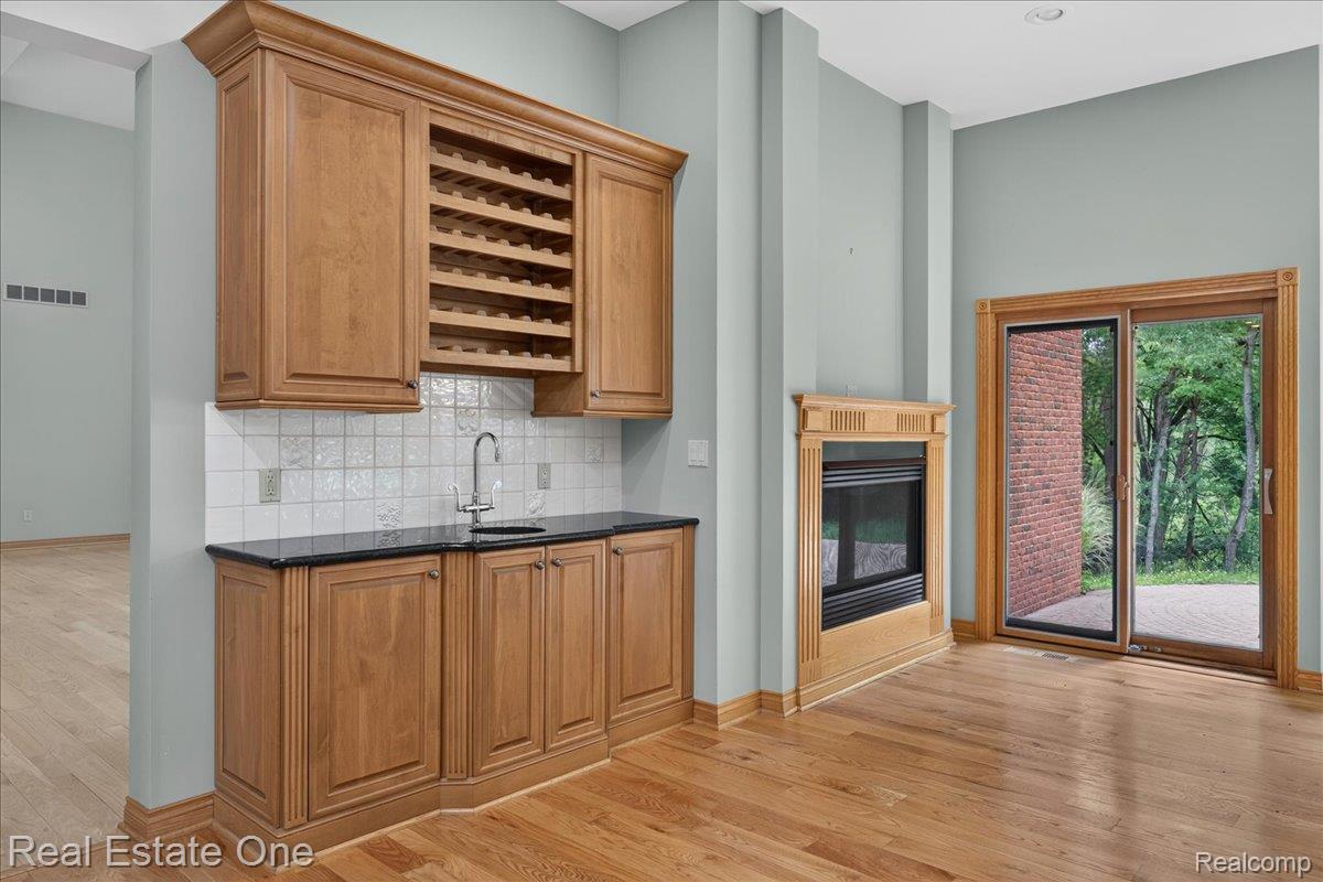 425 Courtney Road Leonard, MI 48367 - Photo 21 of 89 Integrated wet bar featuring wood cabinetry, stone countertop, sink, and built-in wine storage