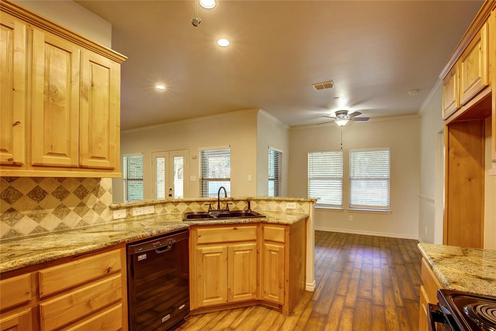 2617 Kirby Road Rowlett, TX 75088 - Photo 11 of 39 Kitchen with black appliances, decorative backsplash, ornamental molding, light stone countertops, and a peninsula