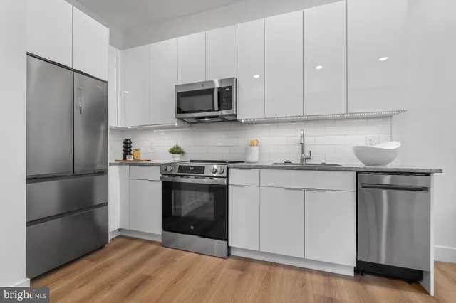 a kitchen with stainless steel appliances granite countertop a refrigerator stove and white cabinets