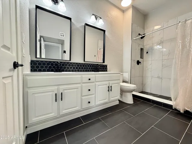 a bathroom with a double vanity sink a toilet and a mirror