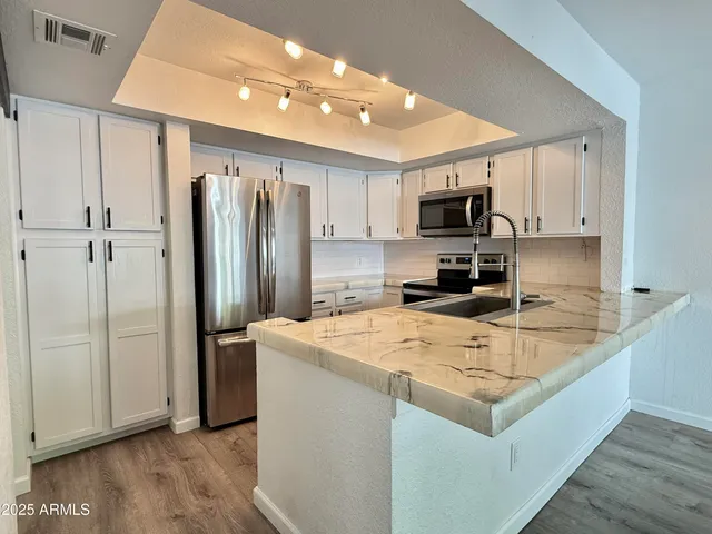 a kitchen with stainless steel appliances a refrigerator sink and microwave