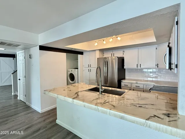 a kitchen with stainless steel appliances kitchen island a refrigerator sink and cabinets