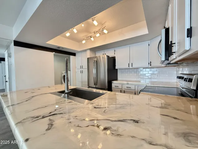 a kitchen with stainless steel appliances kitchen island granite countertop a sink refrigerator and cabinets