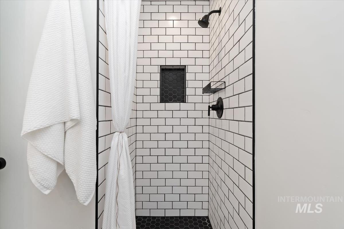 2217 North Middlefield Road Boise, ID 83704 - Photo 25 of 34 Subway tile shower with dark grout, black hexagonal tile floor, and matte black fixtures