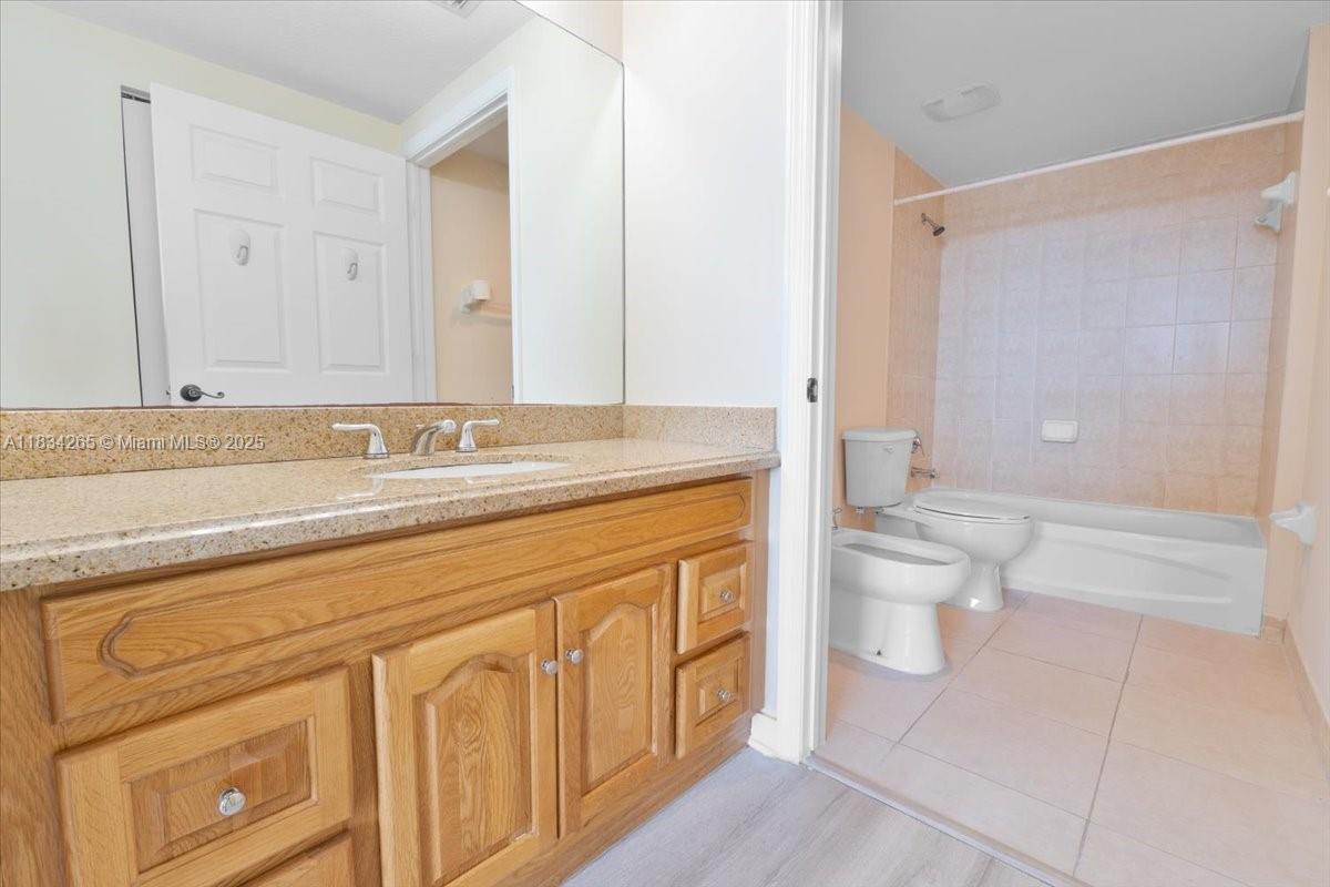 4242 Northwest 2nd Street, Unit 1601 Miami, FL 33126 - Photo 15 of 37 a spacious bathroom with a granite countertop toilet sink and mirror