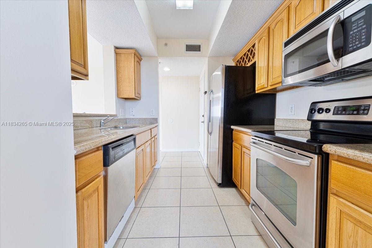 4242 Northwest 2nd Street, Unit 1601 Miami, FL 33126 - Photo 19 of 37 a kitchen with stainless steel appliances granite countertop a stove a sink and a microwave