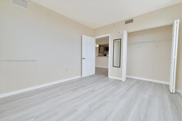 an empty room with wooden floor & closet and windows