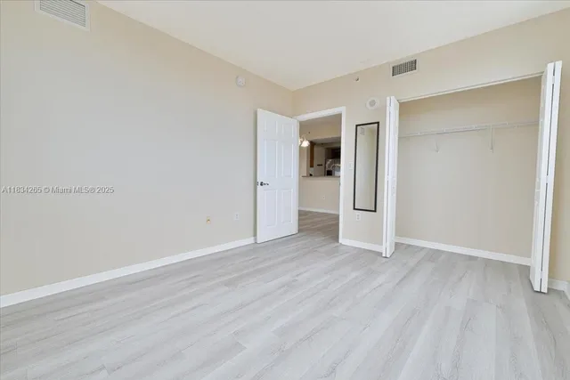 an empty room with wooden floor & closet and windows