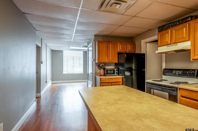 a kitchen with stainless steel appliances kitchen island granite countertop a refrigerator a stove top oven a sink and dishwasher