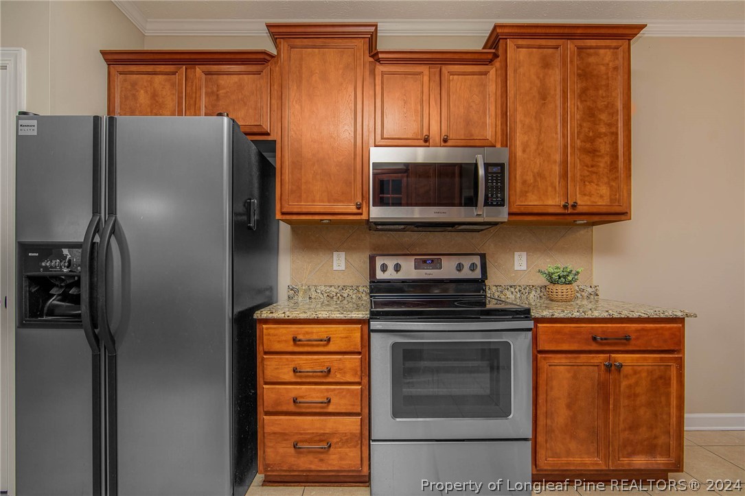 3304 Geyser Peak Road Fayetteville, NC 28306 - Photo 15 of 39 a kitchen with granite countertop a refrigerator stove and microwave