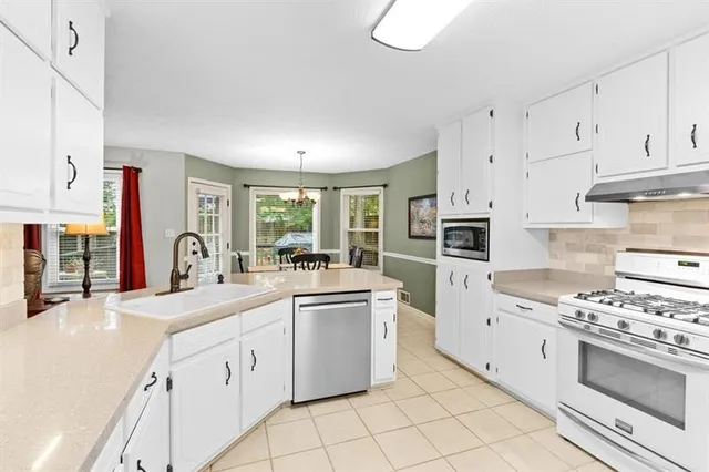 a kitchen with white cabinets and appliances