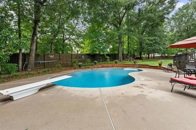 a view of a swimming pool with a patio and a yard