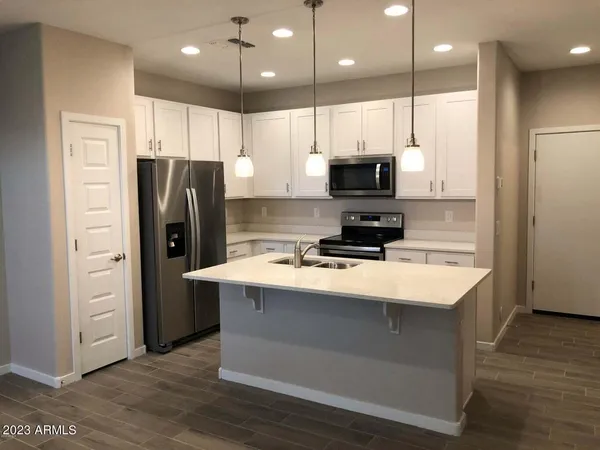 a kitchen with kitchen island a refrigerator a stove a sink and a oven with wooden floor