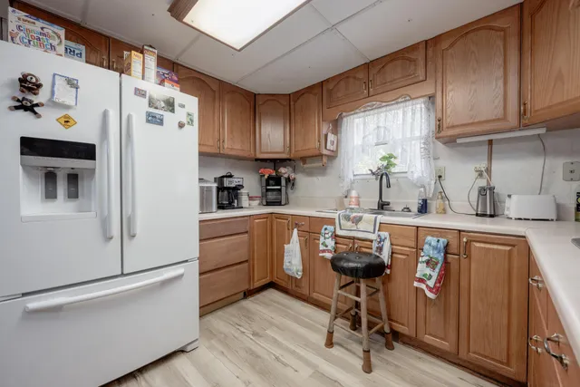 a kitchen with granite countertop a white refrigerator and wooden cabinets