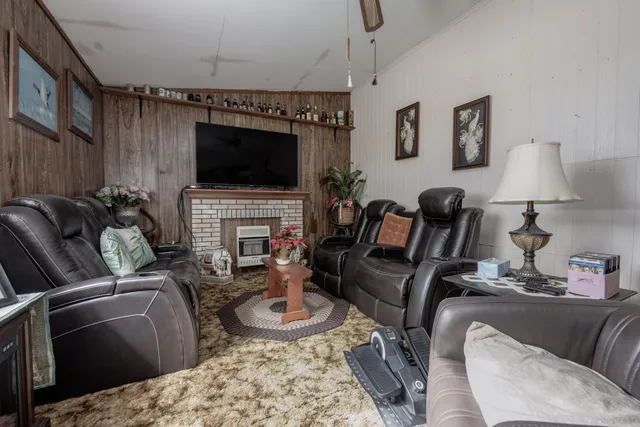 a room with furniture a rug kitchen view and a fireplace