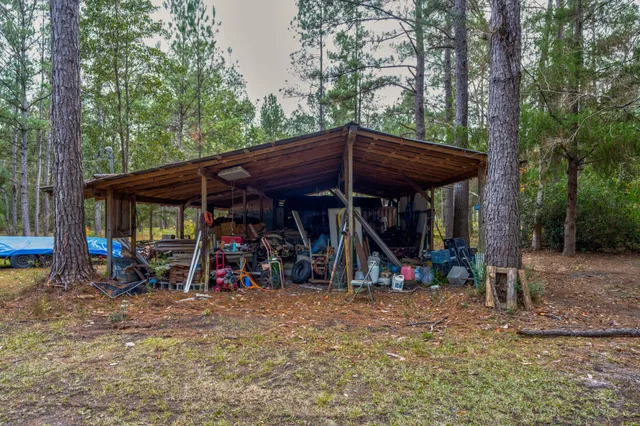 a view of a wooden house with a yard and large trees