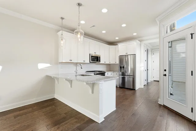 a kitchen with stainless steel appliances granite countertop white cabinets and a refrigerator
