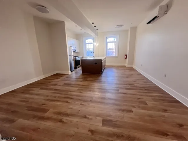 a view of a big room with wooden floor and a kitchen