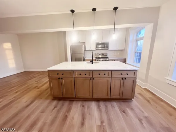 a kitchen with a sink a stove cabinets and wooden floor