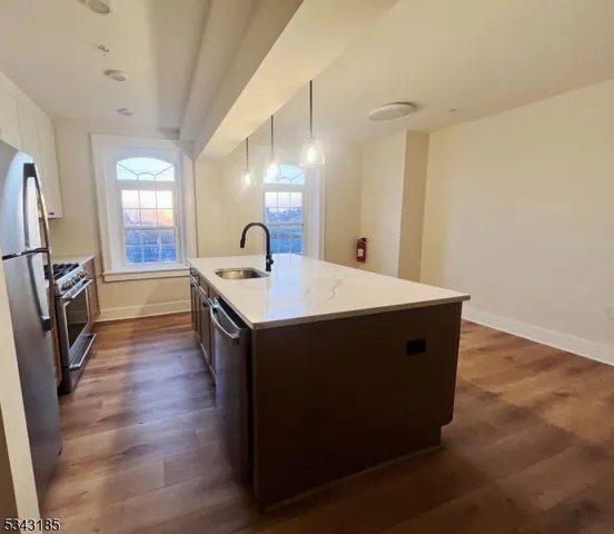 a kitchen with a sink a microwave a refrigerator and wooden floor