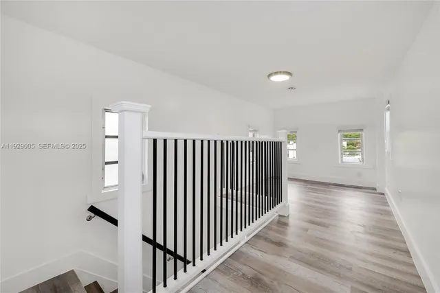 a view of a hallway with wooden floor and stairs