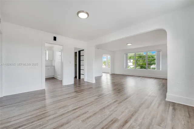 a view of an empty room with window and wooden floor