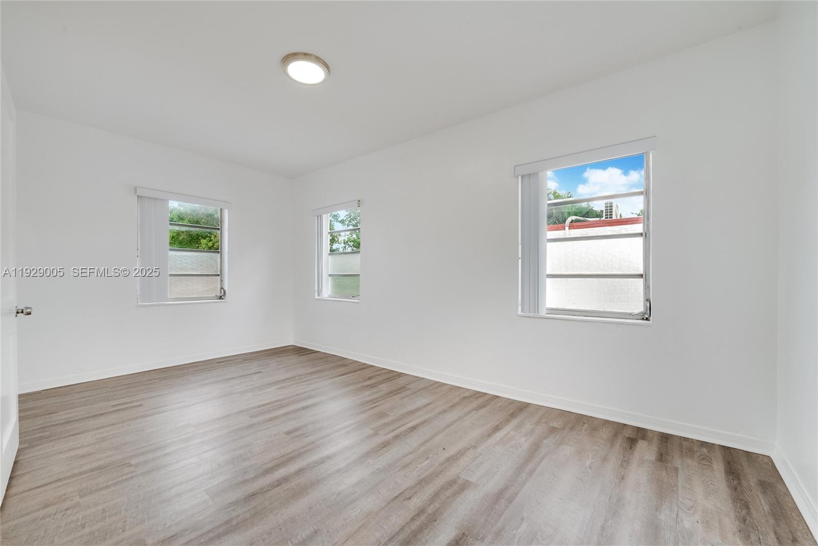 1736 Southwest 9th Street, Unit 1738 Miami, FL 33135 - Photo 8 of 15 an empty room with wooden floor and windows