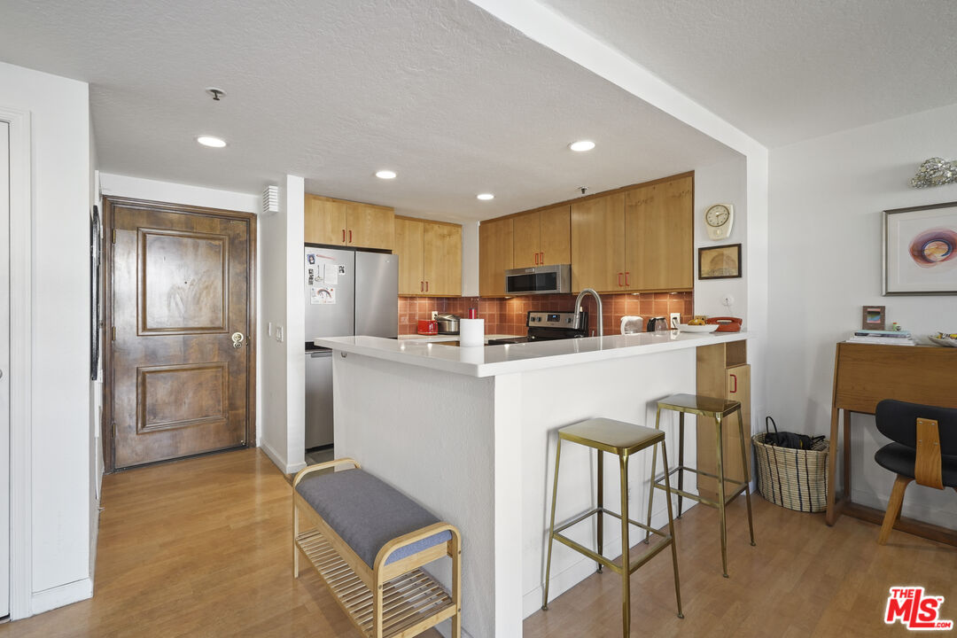 880 West 1st Street, Unit 604 Los Angeles, CA 90012 - Photo 16 of 60 a kitchen with refrigerator cabinets dining table and chairs