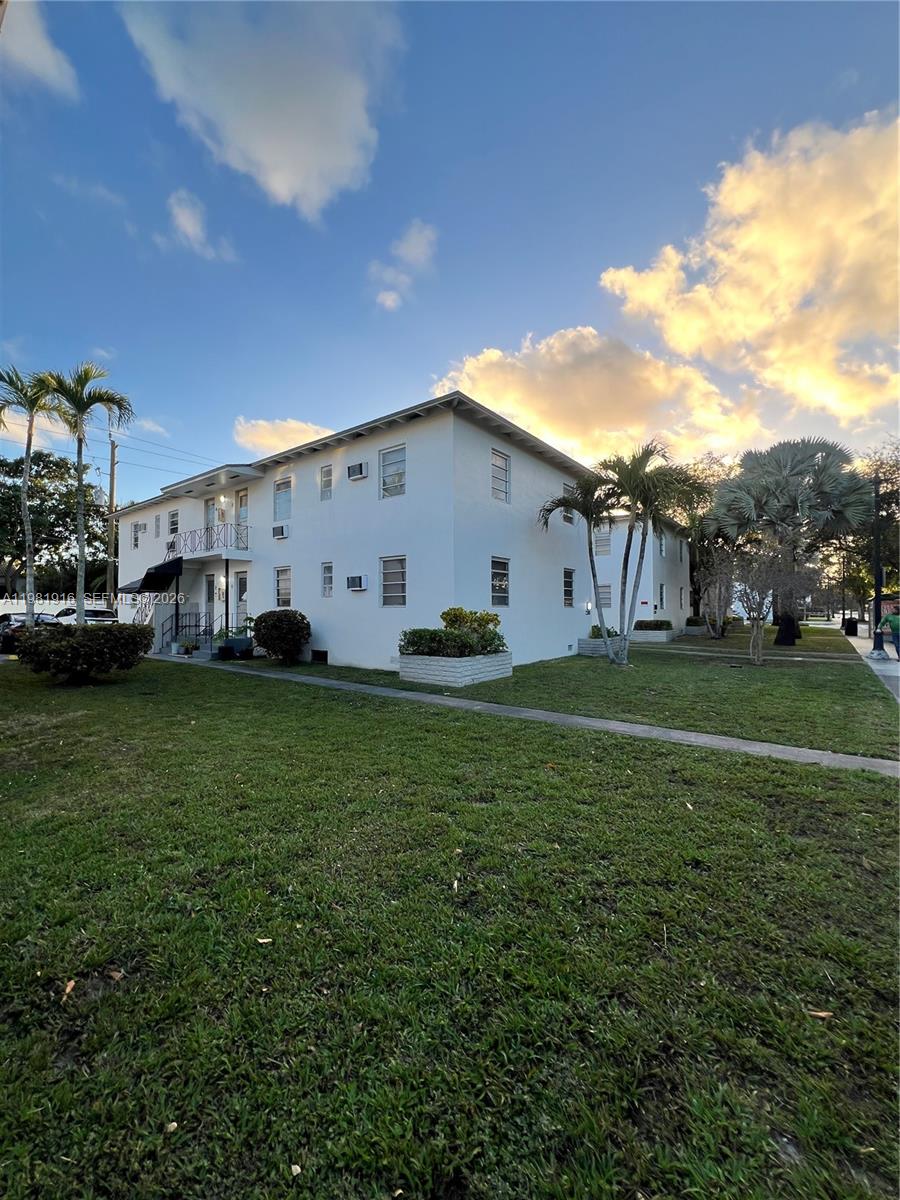 2390 Southwest 22nd Street, Unit 4 Miami, FL 33145 - Photo 2 of 10 a view of a white house in front of a big yard with potted plants and large trees