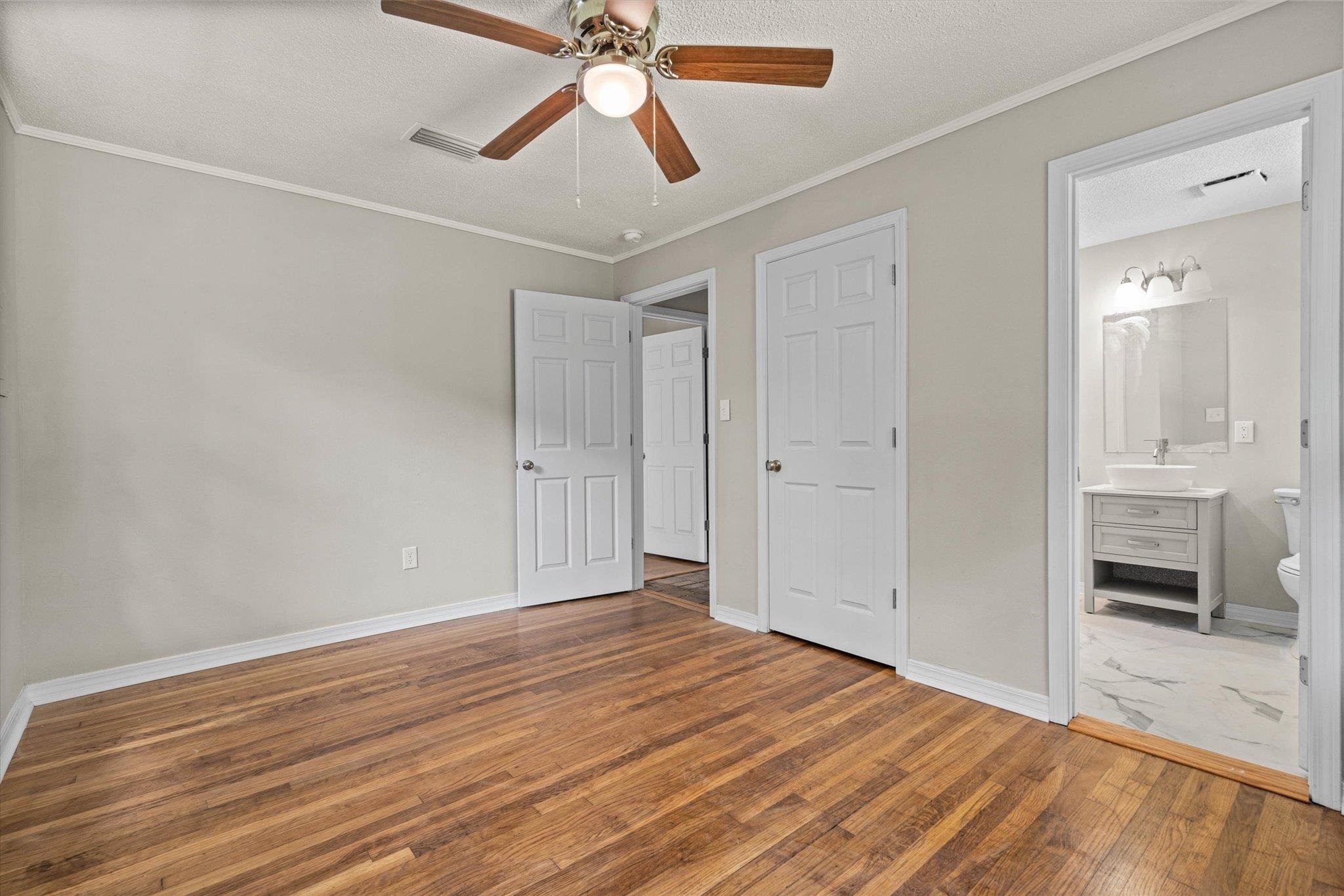 4700 Bit And Spur Road Mobile, AL 36608 - Photo 11 of 21 Unfurnished bedroom featuring a sink, baseboards, visible vents, hardwood / wood-style floors, and ornamental molding