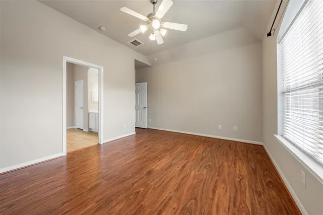 an empty room with wooden floor and windows