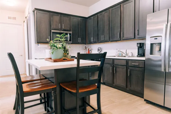 a kitchen with stainless steel appliances a table chairs and a refrigerator
