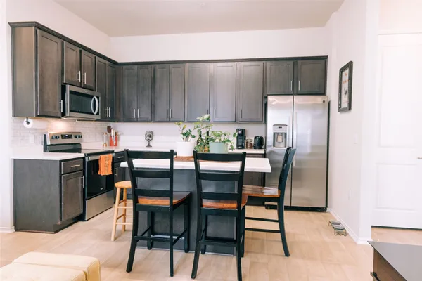 a kitchen with stainless steel appliances a table chairs microwave and refrigerator