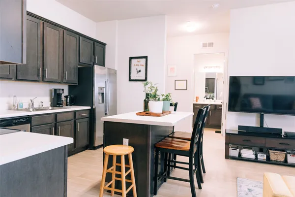a kitchen with stainless steel appliances a dining table chairs and a refrigerator