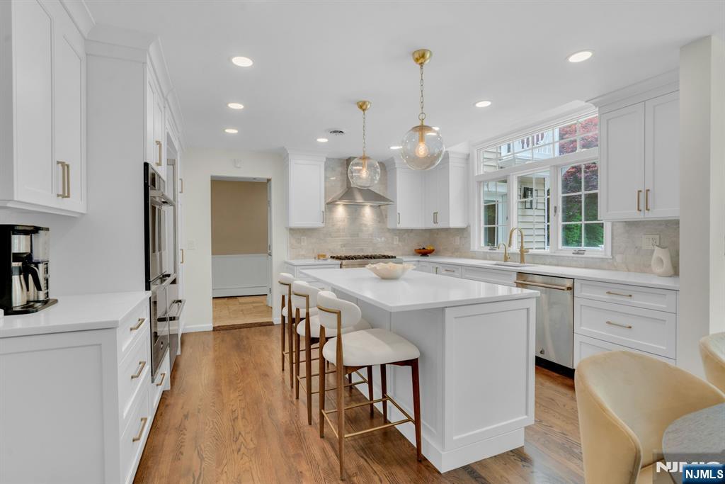 48 Hopper Farm Road Upper Saddle River, NJ 07458 - Photo 11 of 43 a kitchen with kitchen island a stove a sink a refrigerator and a dining table with wooden floor
