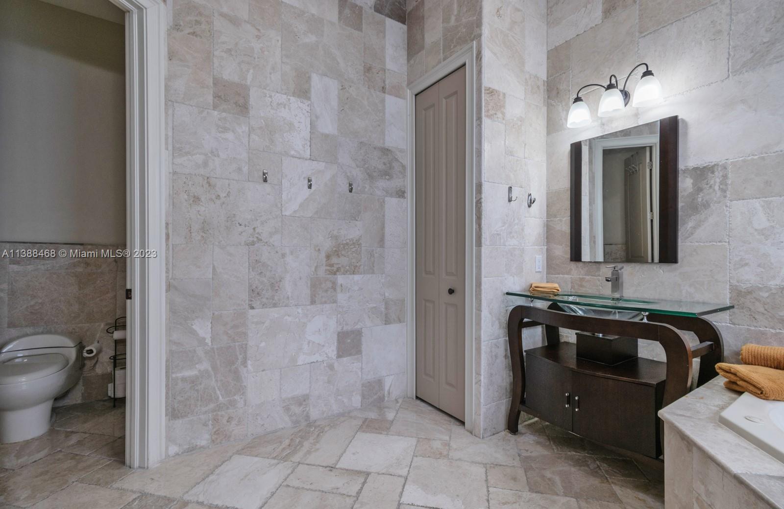 6874 Southwest 57th Terrace Miami, FL 33143 - Photo 17 of 36 a bathroom with a granite countertop sink a toilet and mirror