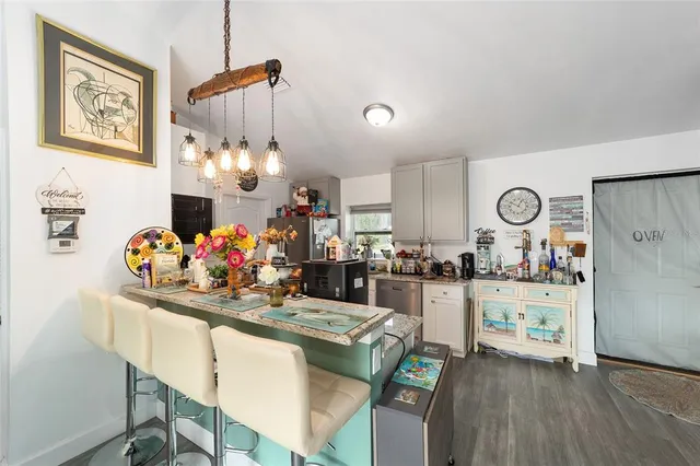 a kitchen with stainless steel appliances kitchen island granite countertop a sink cabinets and wooden floor