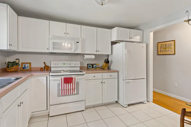 a kitchen with white cabinets and white appliances