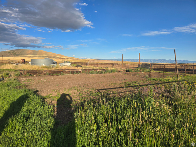 34200 Coulam Road Swan Lake, ID 83281 - Photo 5 of 24 Expansive outdoor area featuring fencing, a large metal tank, and visible mountain ranges in the background