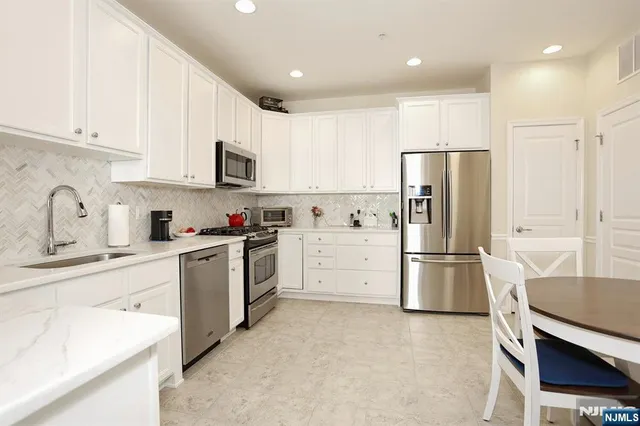 a kitchen with stainless steel appliances a refrigerator sink and white cabinets