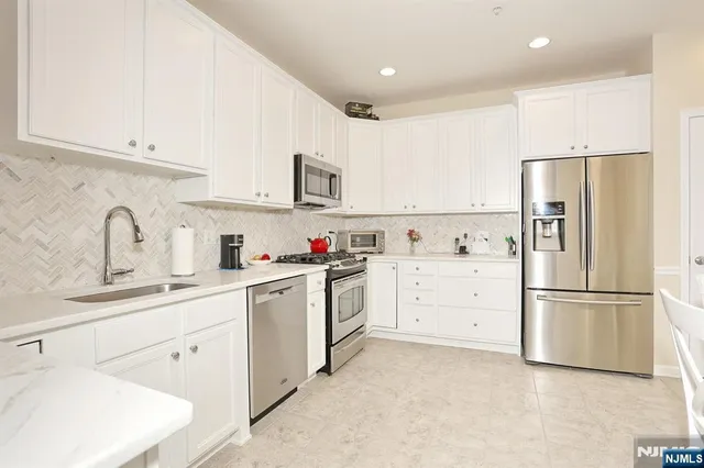 a kitchen with white cabinets and stainless steel appliances