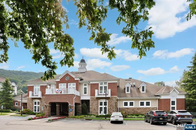 a front view of a building with lot of cars and trees