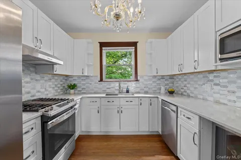 a kitchen with white cabinets stainless steel appliances and window