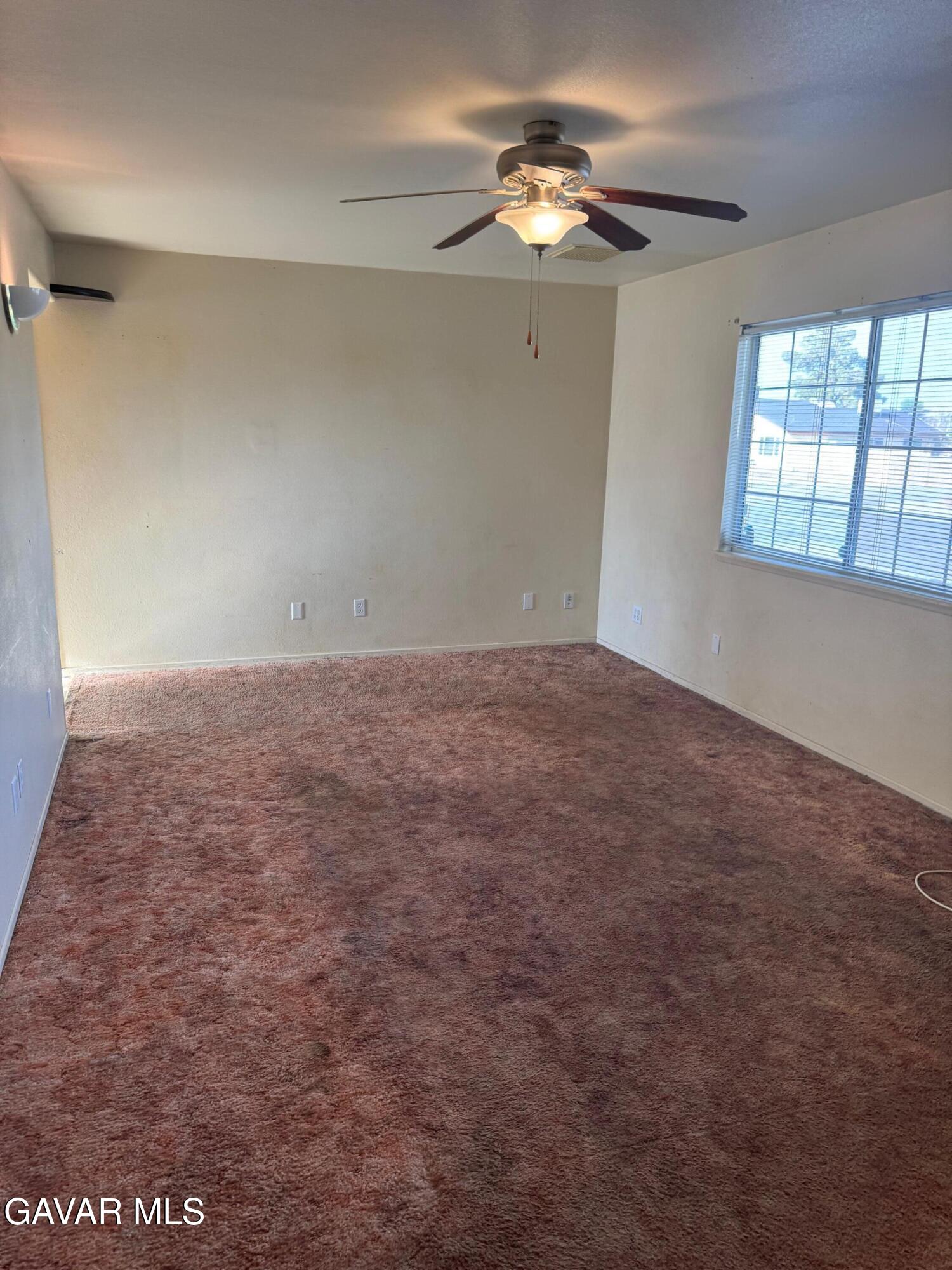 1105 South McCall Street Ridgecrest, CA 93555 - Photo 4 of 12 an empty room with windows and chandelier fan