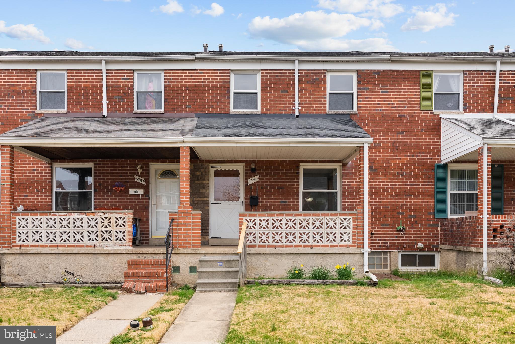 front view of a brick house with a yard and a car