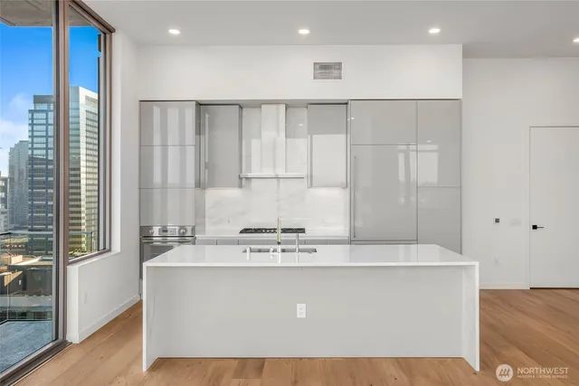 a view of kitchen with stainless steel appliances granite countertop white cabinets and window