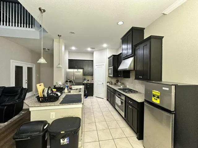 a kitchen with stainless steel appliances kitchen island granite countertop a refrigerator and a stove top oven