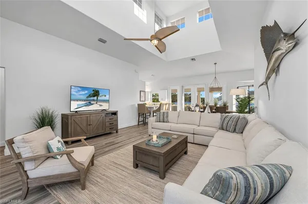 a living room with furniture kitchen view and a wooden floor