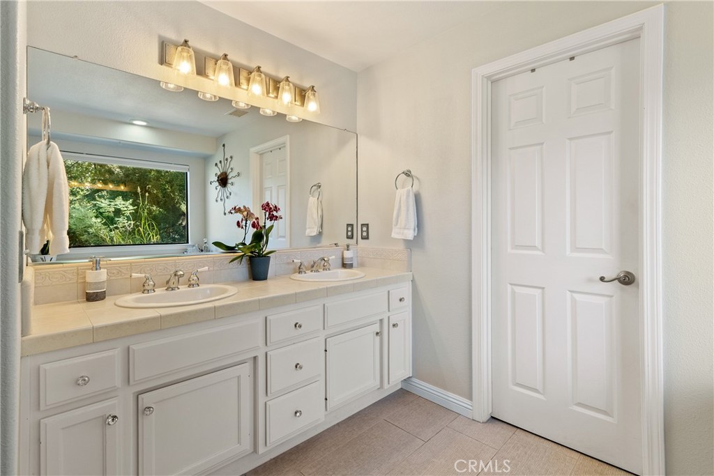 11625 Cenegal Road Atascadero, CA 93422 - Photo 20 of 65 The ensuite bathroom has a sizable double sink vanity illuminated with an attractive light. The water closet with walk-in shower is past the door.